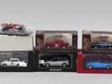 quatre modèles réduits de voitures dans des boîtes posées sur une table
