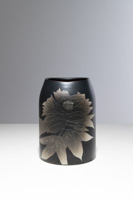 un vase noir orné d'une fleur, posé sur une table