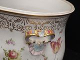 a large white bowl with a gold handle on a black background
