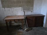a wooden table with a broom on it in the corner of a room