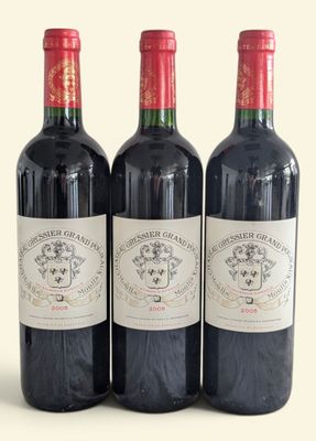 three bottles of red wine are lined up on a white surface