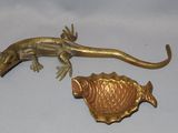 a gold lizard and a gold fish on a white surface