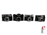 four cameras are lined up in a row on a white surface