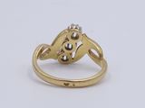 a close up of a gold and diamond ring on a white surface