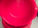 une personne tenant un bol en plastique rouge posé sur une table