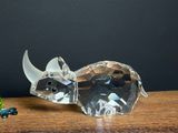 crystal rhino figurine sitting on top of a wooden table next to beads