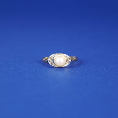 une bague ovale sertie d'une perle et de diamants sur fond bleu