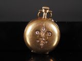 a gold pocket watch with a fleur de lis design on it