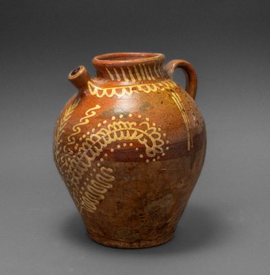 an old brown vase with designs on it on a gray surface