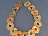 gros plan d'un bracelet en or avec des pierres multicolores