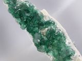 a close up of a piece of green crystals on a white surface