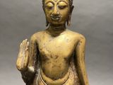 statue of a seated buddha holding a book in his right hand