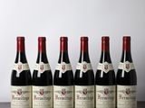 six bottles of red wine lined up on a wooden table