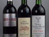 three bottles of red wine are lined up on a gray surface