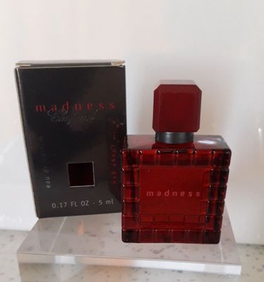 une image représentant un flacon de parfum rouge à côté d'une boîte noire