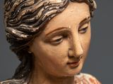 an old statue of a woman with long hair and a flower in her hand