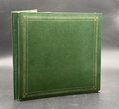 a green leather book with gold trims on a grey background