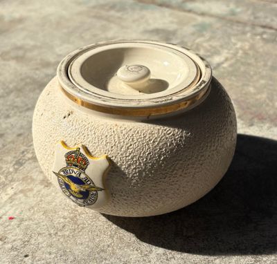 un petit pot muni d'un couvercle, posé par terre