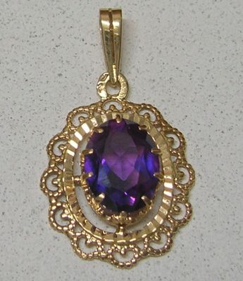 une image représentant un pendentif en or orné d'une pierre violette au centre