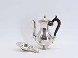 une cafetière et une cuillère en argent posées sur une surface blanche