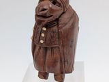 sculpture of a woman in a brown coat and scarf on a white pedestal