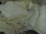 une pile de vêtements blancs au crochet et une paire de ciseaux