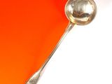 une cuillère en argent avec un manche, sur un fond orange et blanc