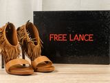 tan fringe sandals with a black box on a wooden table