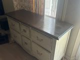 a dresser in the corner of a room next to a window