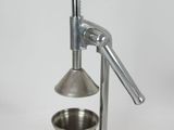 a small metal juicer with a metal cup on it