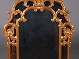 un cadre doré richement décoré surmonté d'un miroir