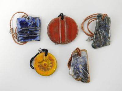 six pendentifs artisanaux en verre et en cuir sur un fond blanc