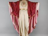 La statue de Jésus porte une robe rouge et tient une croix.
