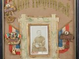 une vieille photo représentant une photo encadrée d'un homme portant des médailles