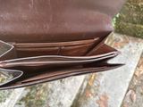 someone is holding a brown purse with two zippers on it