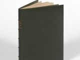 un livre noir à la couverture marron posé sur une surface blanche