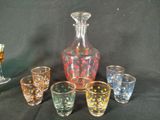five glasses and a decanter sitting on a table