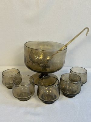 un saladier en verre avec une cuillère et des verres posés sur une table