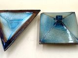 two pieces of glass sitting on a white surface