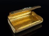 an image of a gold purse with emerald stones on top of it