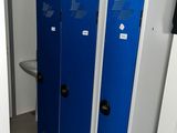 several blue lockers in a bathroom with a sink and a toilet