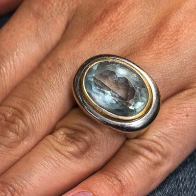 la main d'une femme tenant une bague sertie d'une pierre bleue