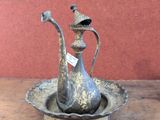 a silver teapot sitting in a bowl on a wooden table
