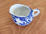 a small blue and white pitcher sitting on a wooden table