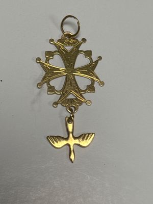an image of a gold cross with a bird charm hanging from it