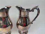 two silver pitchers sitting next to each other on a table