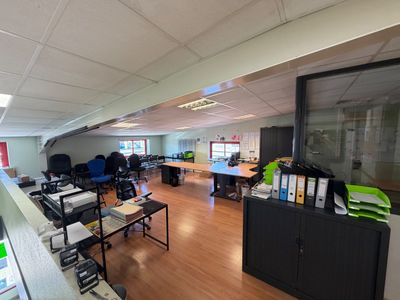 une salle où se trouvent de nombreux bureaux et chaises