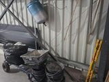 Plusieurs seaux de peinture sont empilés sur un chariot devant un immeuble.