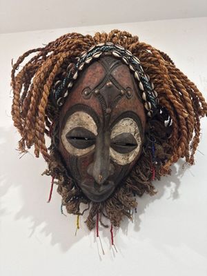 un masque en bois accroché au mur d'une pièce