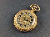 une image d'une montre de poche en or avec des chiffres romains sur le cadran
